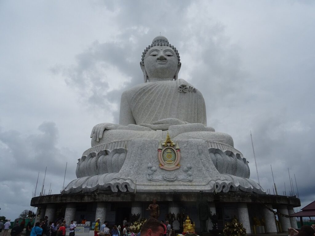 Big Buddha white marble statue on Nakkerd Hill under grey clouds in Phuket