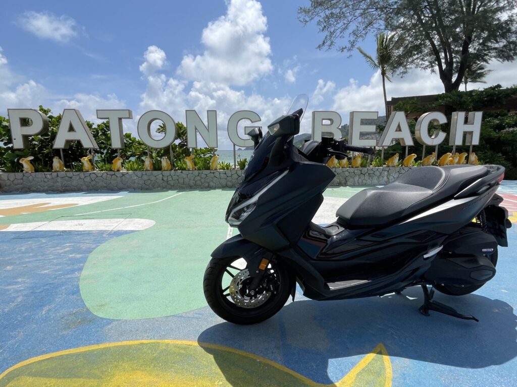 Motorbike Rental at Patong Beach 2 Black Honda Forza 350 scooter in front of the Patong Beach sign, side view