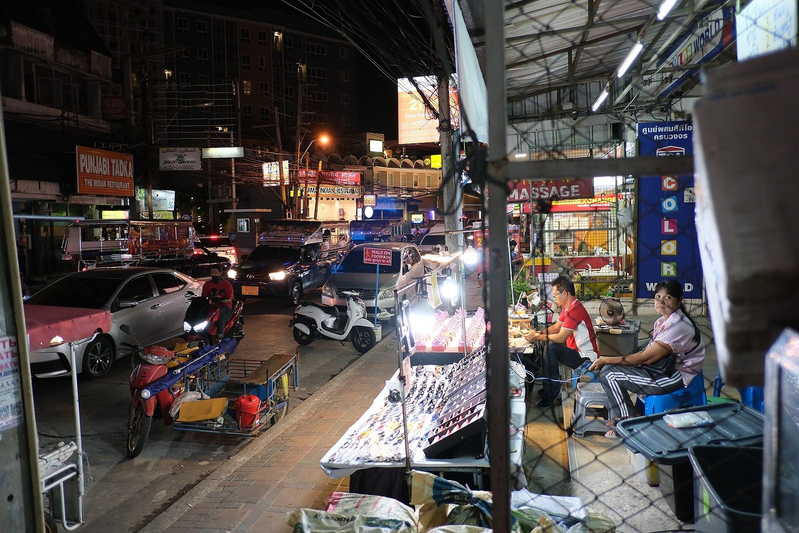 Busy night market street in Thailand with scooters, stalls and people
