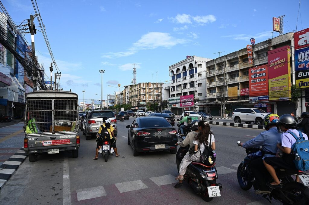 Busy street in Thailand with cars, a songthaew truck and motorbikes sharing the road
