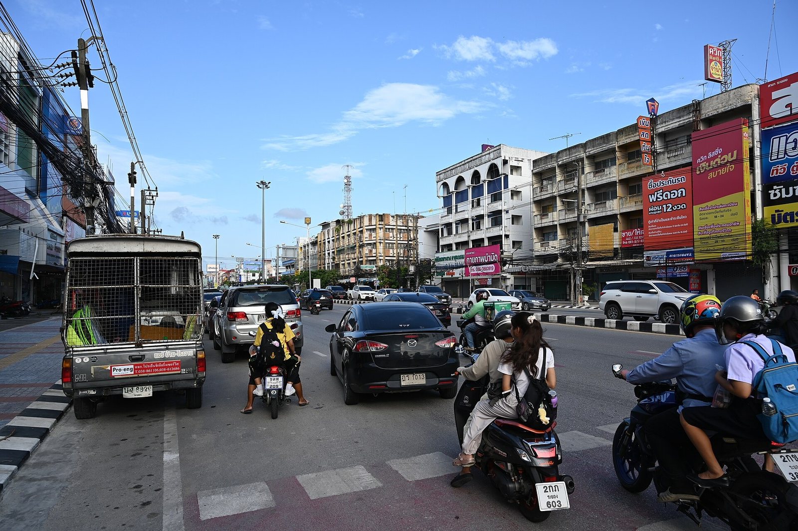 Busy street in Thailand with cars, a songthaew truck and motorbikes sharing the road