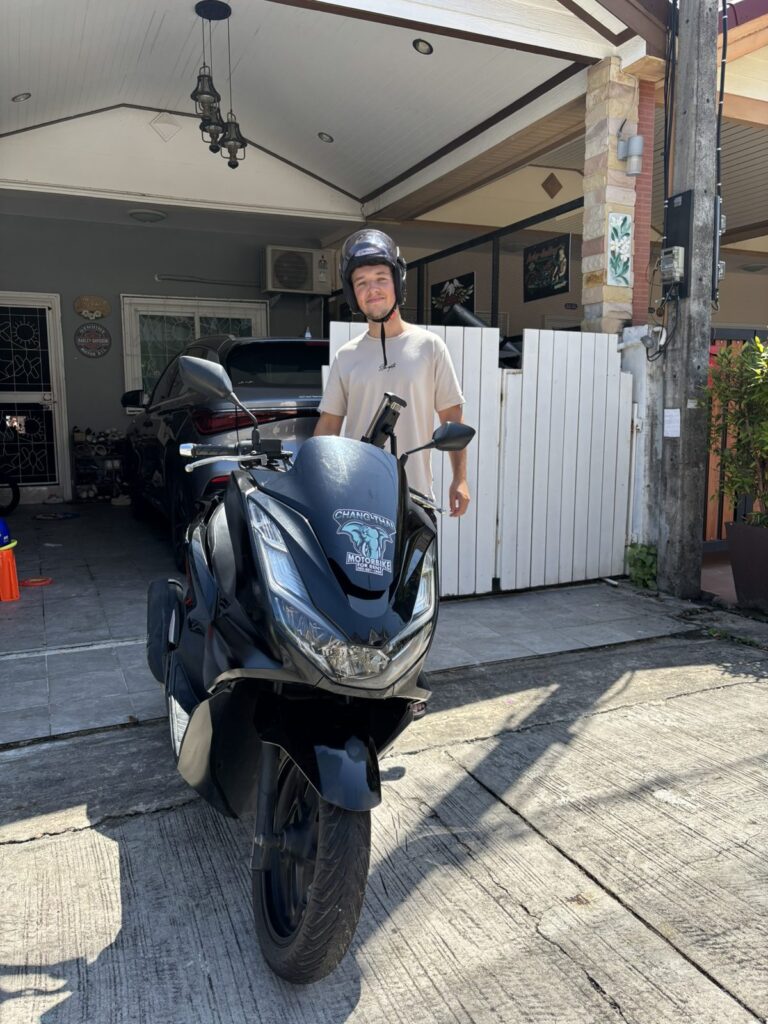 Motorbike Rental in Phuket Old Town 5 Customer standing behind a black Honda PCX scooter in a driveway in Phuket Town