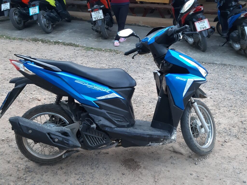 How to Choose & Change Honda Click 125 2026 Engine Oil the Right Way 26 Blue Honda Click 125 scooter parked on a dirt lot, right side view