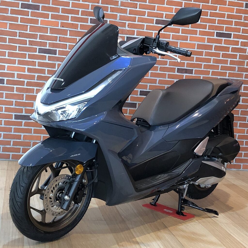 bike rent near me Phuket motorbike rental, professional motorcycle rental service provider Happy to serve every customer. 2 Honda PCX 160 automatic scooter in metallic blue grey beside a brick wall