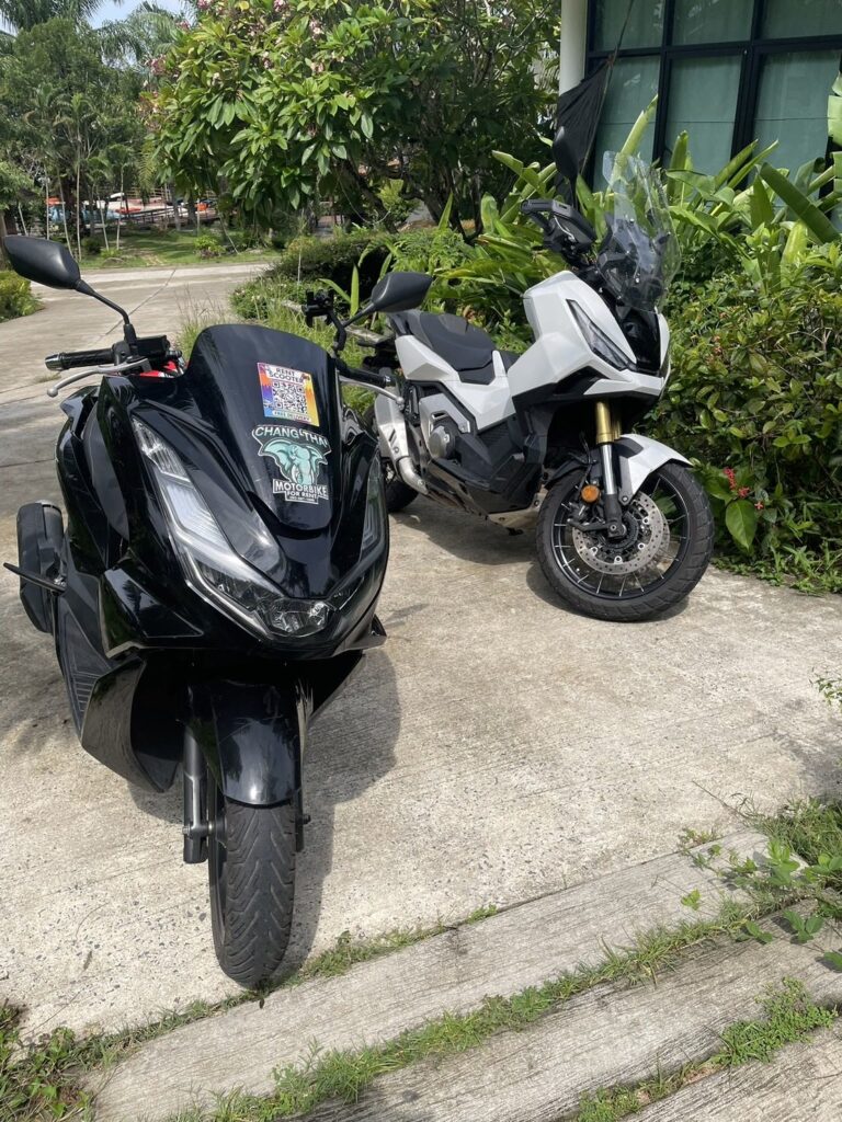 Motorbike Rental at Kata Beach 2 Black Honda PCX and white ADV rental scooters parked beside a green hedge in Kata