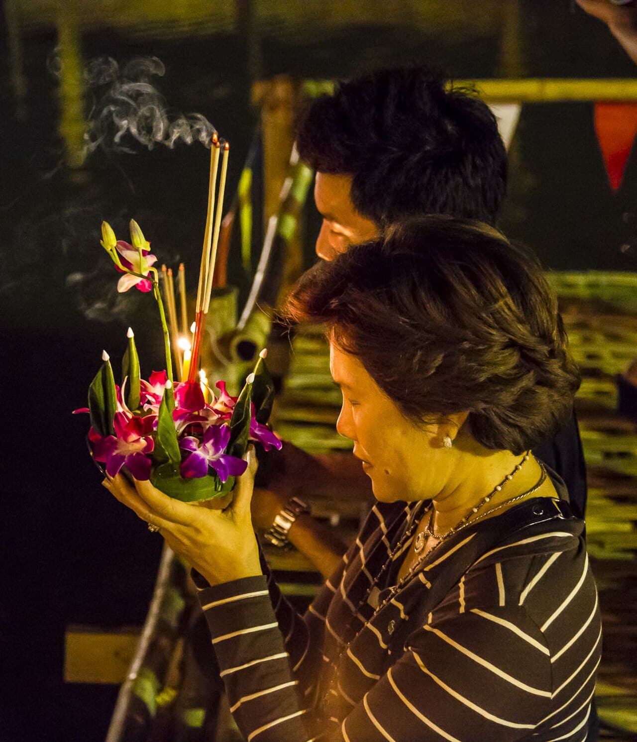 People floating candle-lit krathongs on the water during Loy Krathong in Thailand