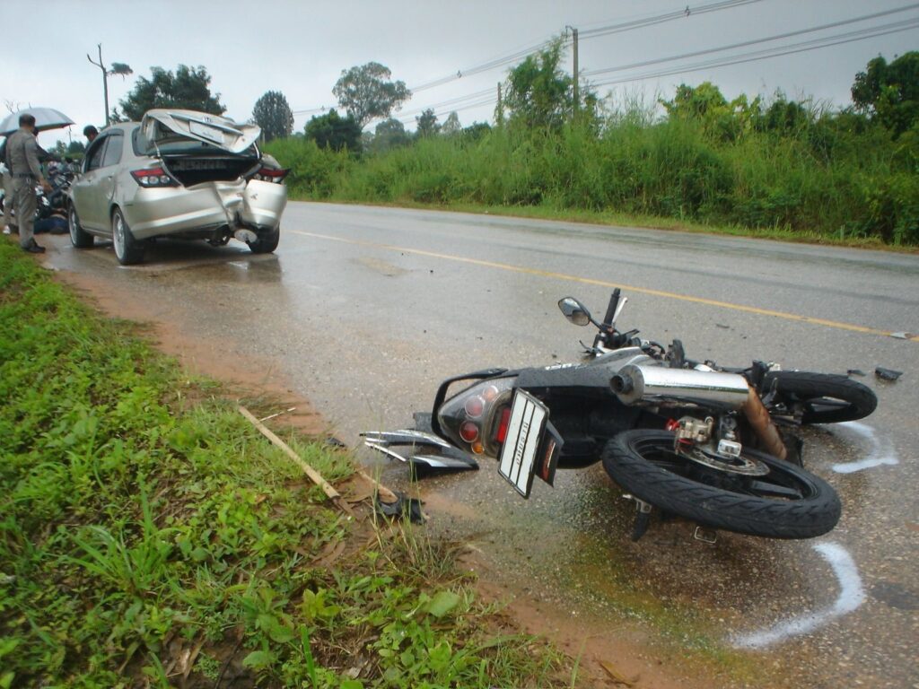 Motorcycle lying on the road after a collision with a car on a wet road in Thailand