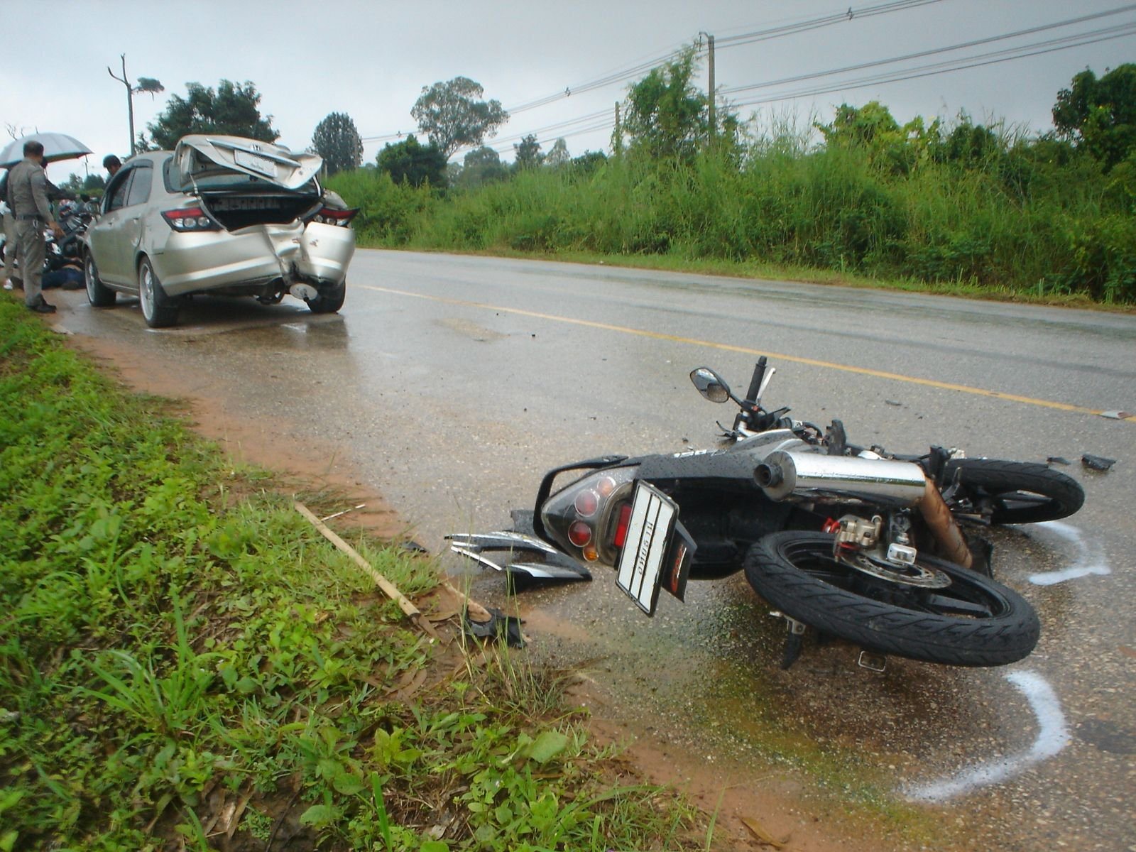 Motorcycle lying on the road after a collision with a car on a wet road in Thailand