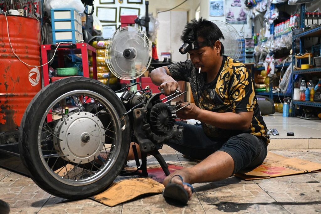 Got a Flat Tire on Your Rental Scooter in Phuket? Here's What Actually Happens 5 Mechanic repairing a motorcycle wheel at a roadside garage in Thailand