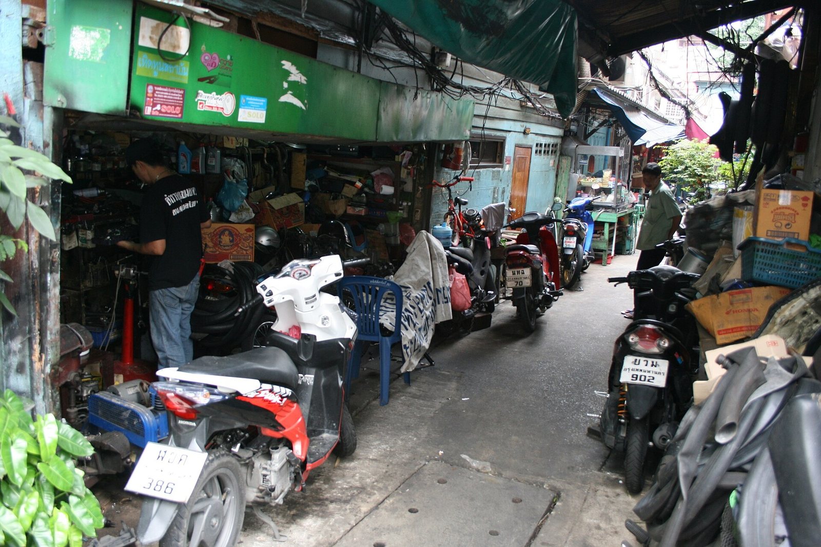 Small motorcycle repair shop on a Bangkok street with scooters parked outside