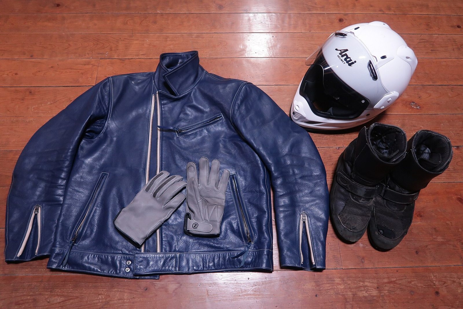Safe Riding Techniques for First-Time Scooter Riders in Phuket 1 Motorcycle riding gear laid out on a wooden floor: helmet, leather jacket, gloves and boots