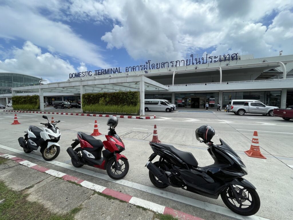 Motorbike Rental at Phuket International Airport 2 Rows of rental scooters parked at the kerb outside the Domestic Terminal at Phuket Airport