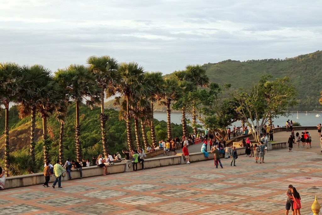 Two-Up Touring on the Honda PCX 160: Real Routes for Couples in Phuket 3 Visitors on the viewing terrace at Promthep Cape in Phuket with palm trees and the sea behind