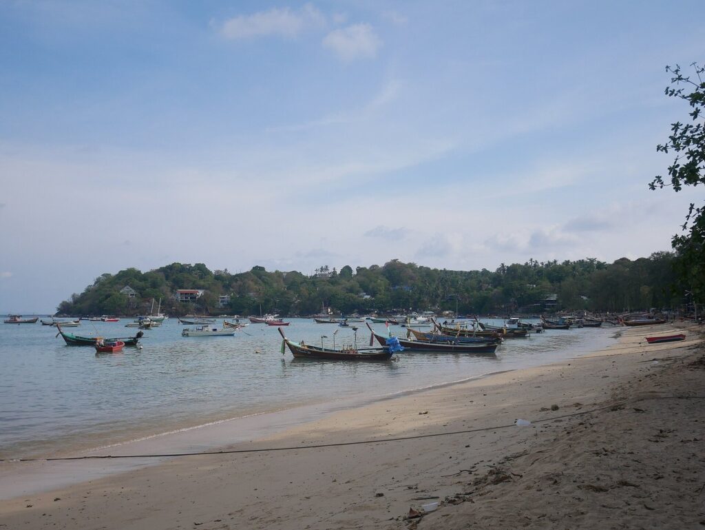 Digital Nomad Guide to Phuket: Best Areas to Base Yourself (and Get Around by Scooter) 2026 3 Fishing longtail boats along the shoreline at Rawai Beach in Phuket