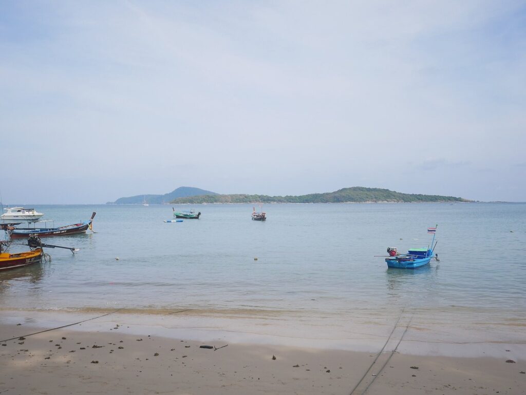 Honda PCX 160 vs Yamaha NMAX 155 vs Honda ADV 160 — Which Scooter Should You Rent in Phuket? (2026 Guide) 4 Longtail boats anchored off Rawai Beach in Phuket with an island in the distance