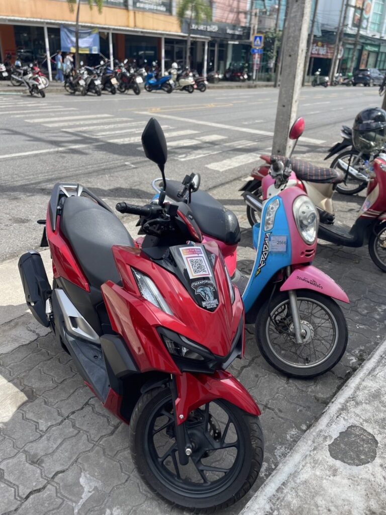 Motorbike Rental at Surin Beach 4 Red Honda scooter and a pink scooter parked on the pavement