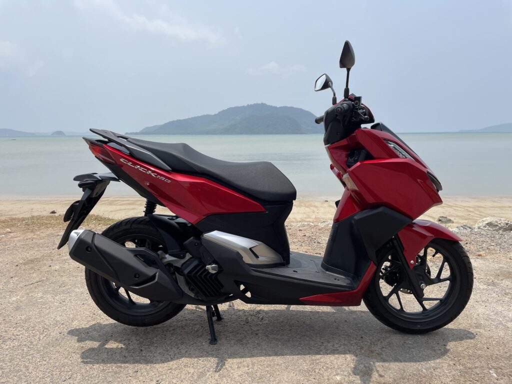 Motorbike Rental at Rawai 3 Red Honda scooter parked on the shore at Rawai with the bay and hills behind