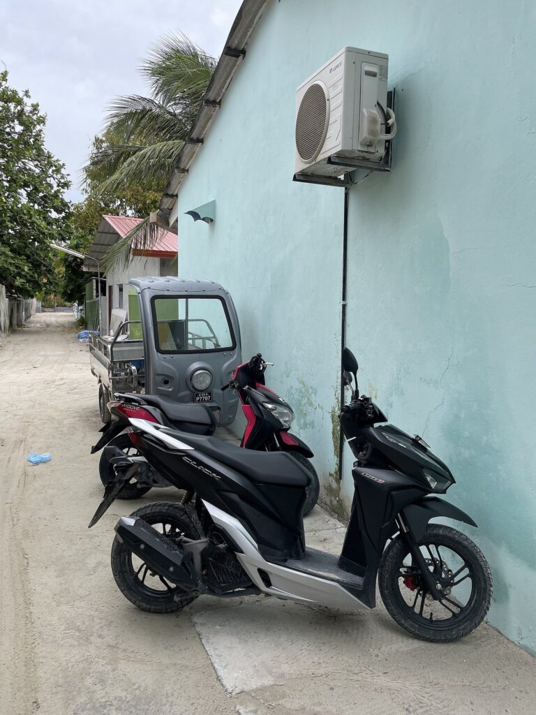 Storing a Honda Click 125 2026 for Months: How to Park Long-Term Without Damage 25 Black Honda scooters parked against a pale wall beside a building