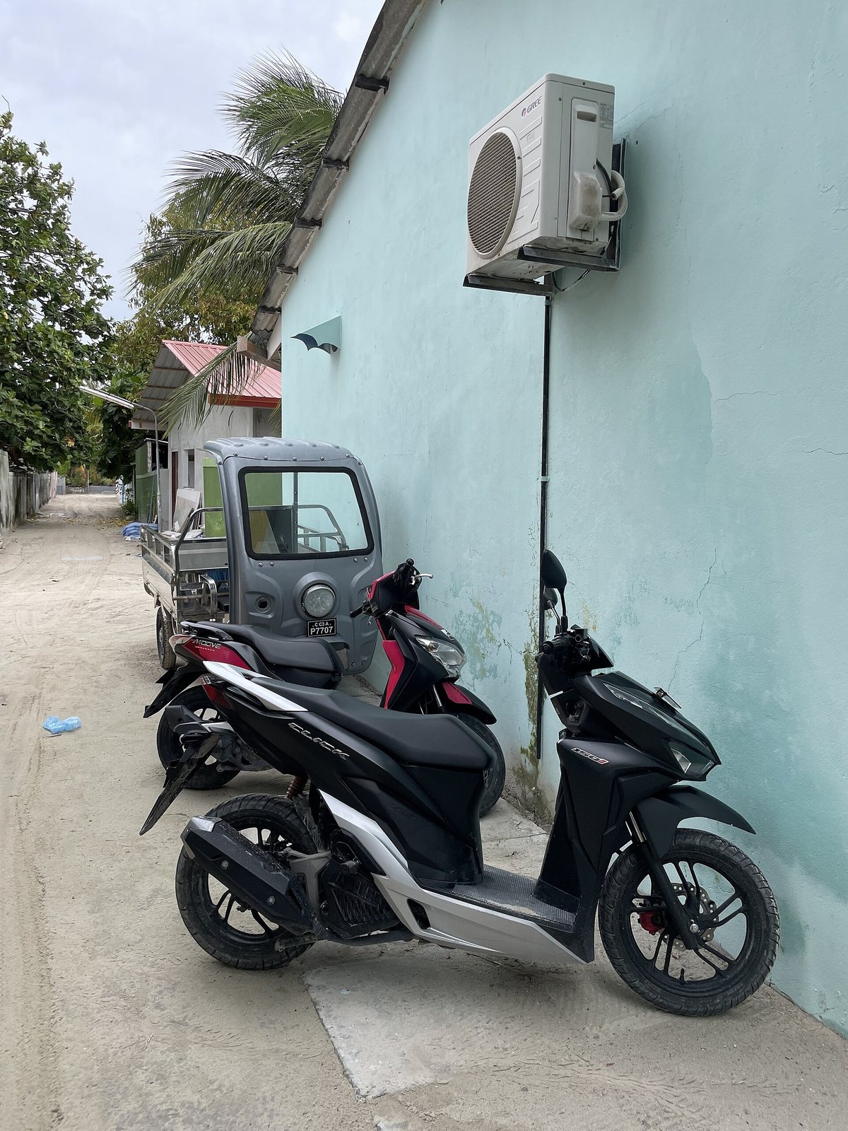 Storing a Honda Click 125 2026 for Months: How to Park Long-Term Without Damage 1 Black Honda scooters parked against a pale wall beside a building