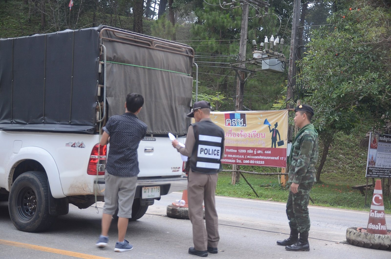 Thai police officers checking a driver at a roadside checkpoint