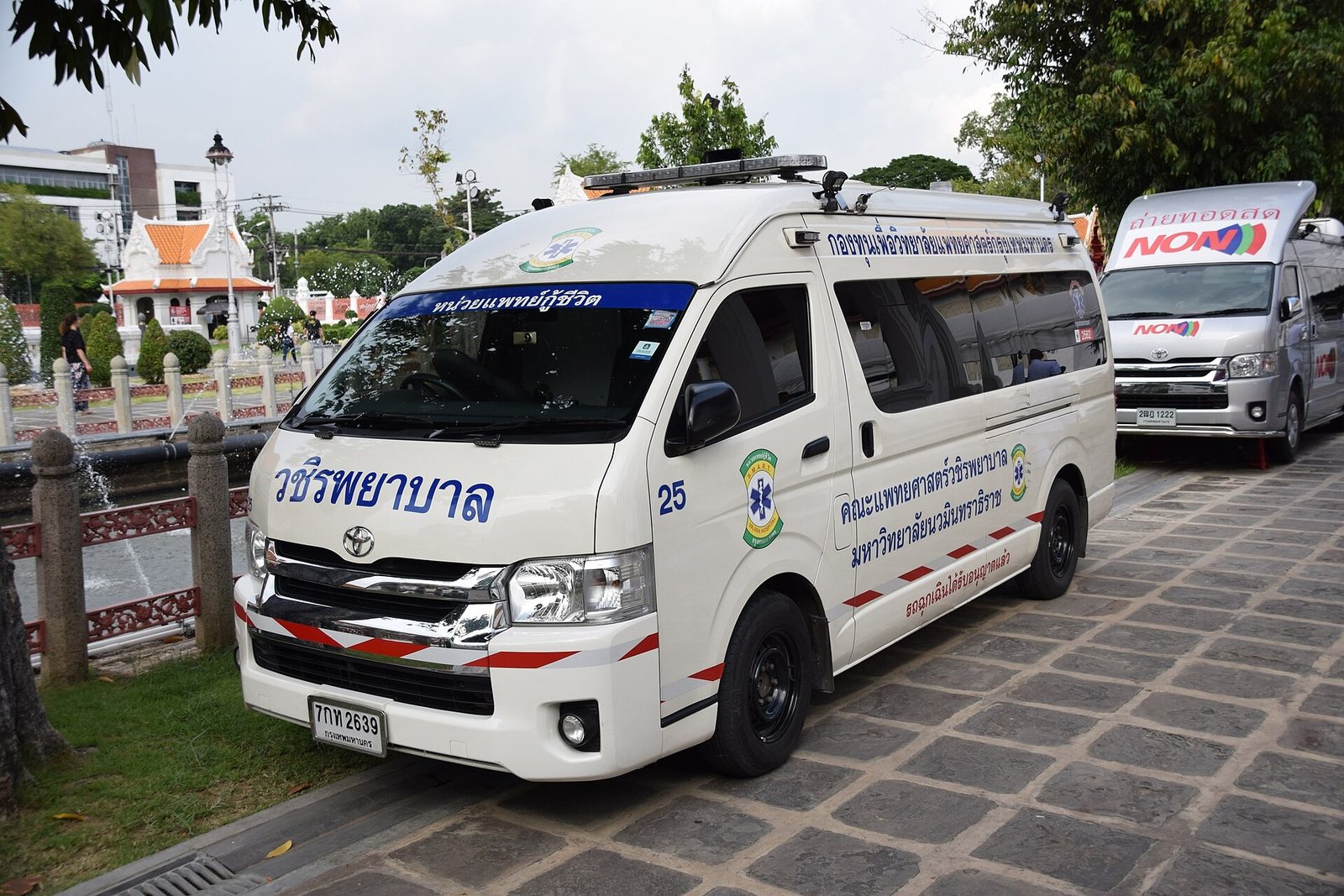 Thai ambulance van parked at the roadside beside a temple wall