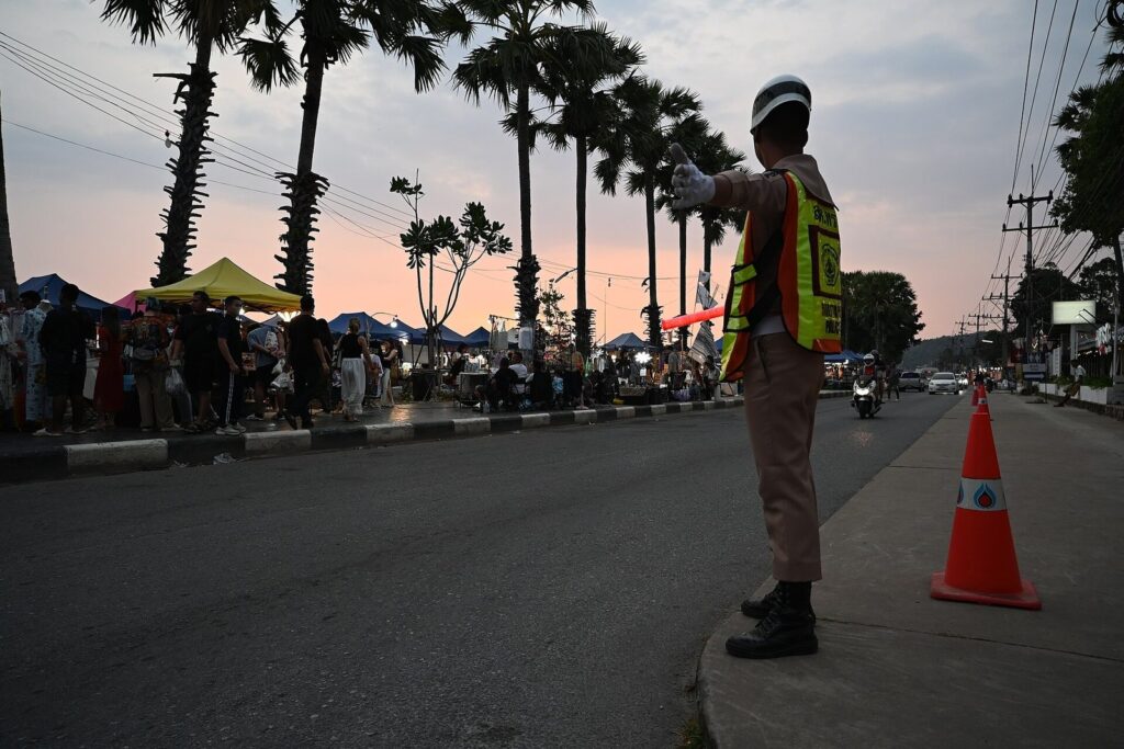 How to Ride a Motorbike Safely in Phuket: Your Guide to Correct Helmet Use 27 Traffic officer in a reflective vest directing traffic on a Thai road at dusk