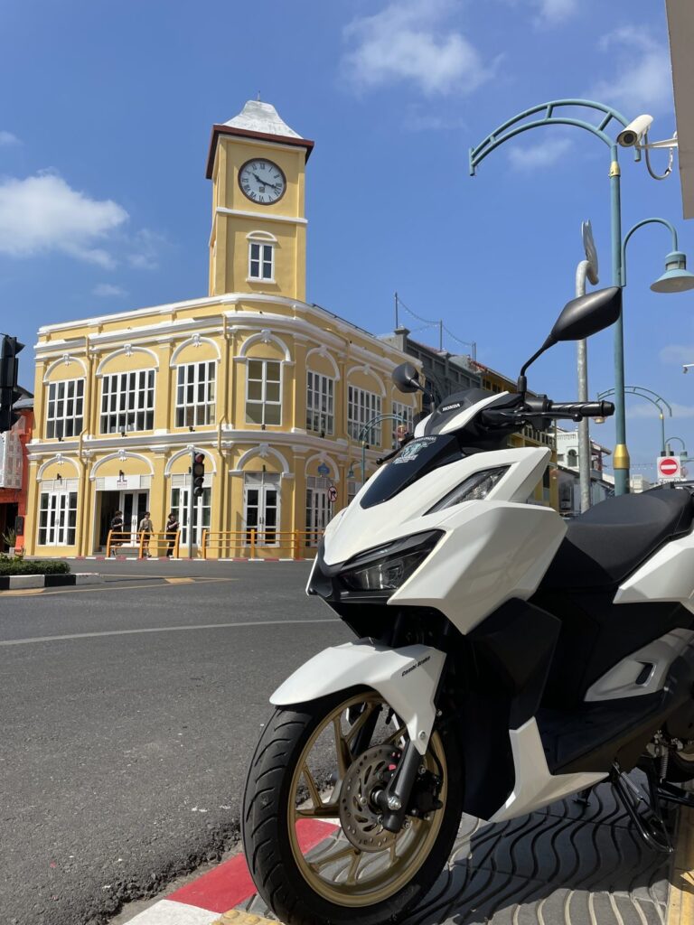 Motorbike Rental in Phuket Old Town 2 White Honda PCX scooter parked in front of the yellow clock-tower building in Phuket Old Town